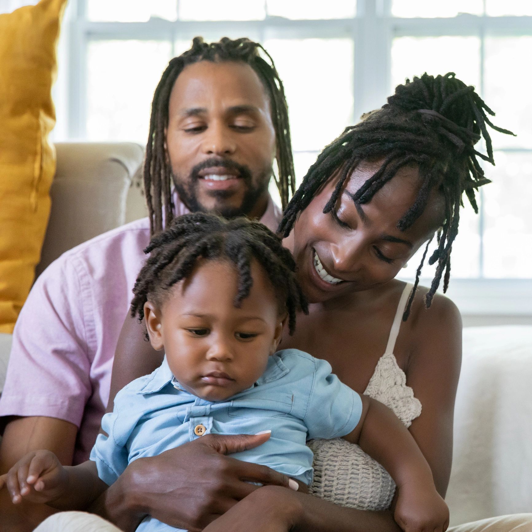 Black parents holding their young child together at home